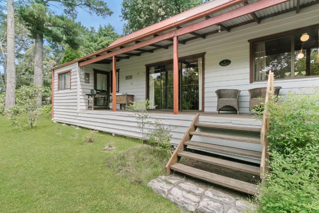 a home with a porch and stairs to the front of it at Arcadia in Wentworth Falls