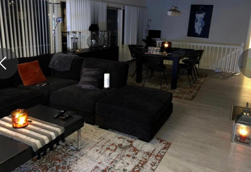 ein Wohnzimmer mit einem schwarzen Sofa und einem Tisch in der Unterkunft Family House in Drammen