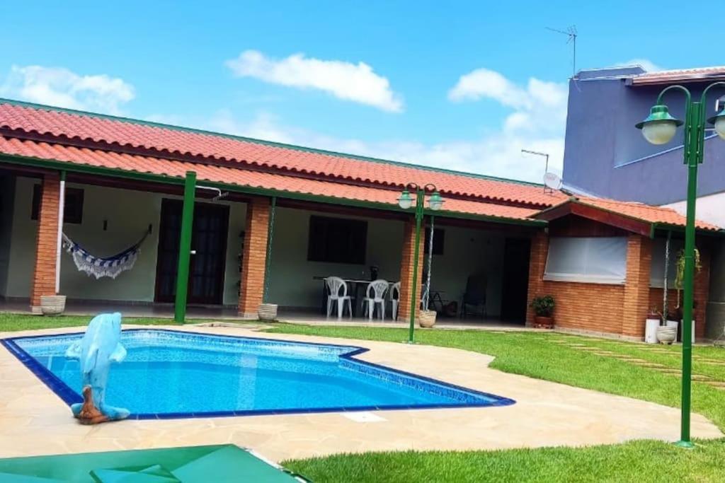 a person standing in front of a house with a swimming pool at Casa dos Villares in Águas de São Pedro