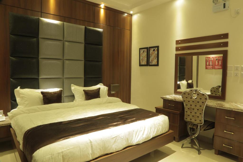 a bedroom with a bed and a desk and a mirror at Kadi Hotel in Najran