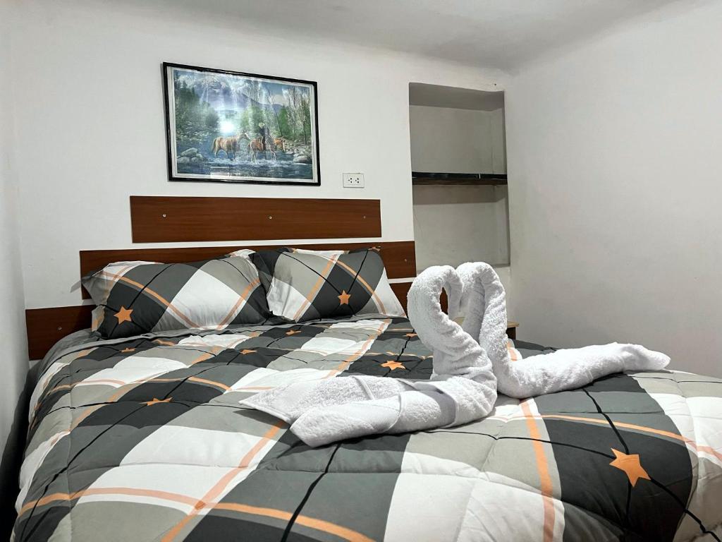Un dormitorio con una cama con cisnes. en Hospedaje Rumiñahui, en Ollantaytambo
