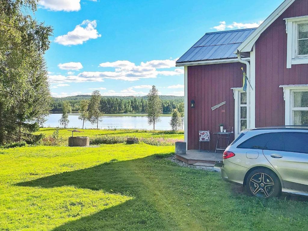 um carro estacionado em frente a uma casa vermelha com um lago em Holiday home BJURHOLM II em Bjurholm