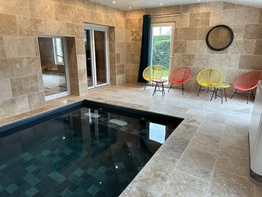a swimming pool in a house with chairs and tables at Gite 5 chambres, piscine intérieure, proche du Der 