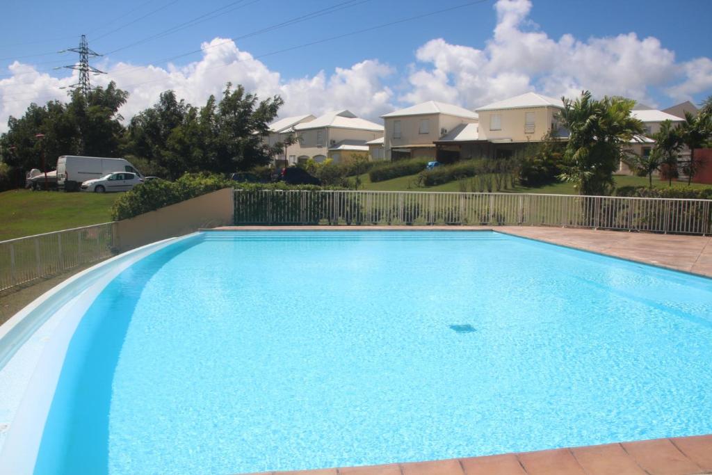 a large blue swimming pool with houses in the background at les Aliceas appartement cosy in Baie-Mahault