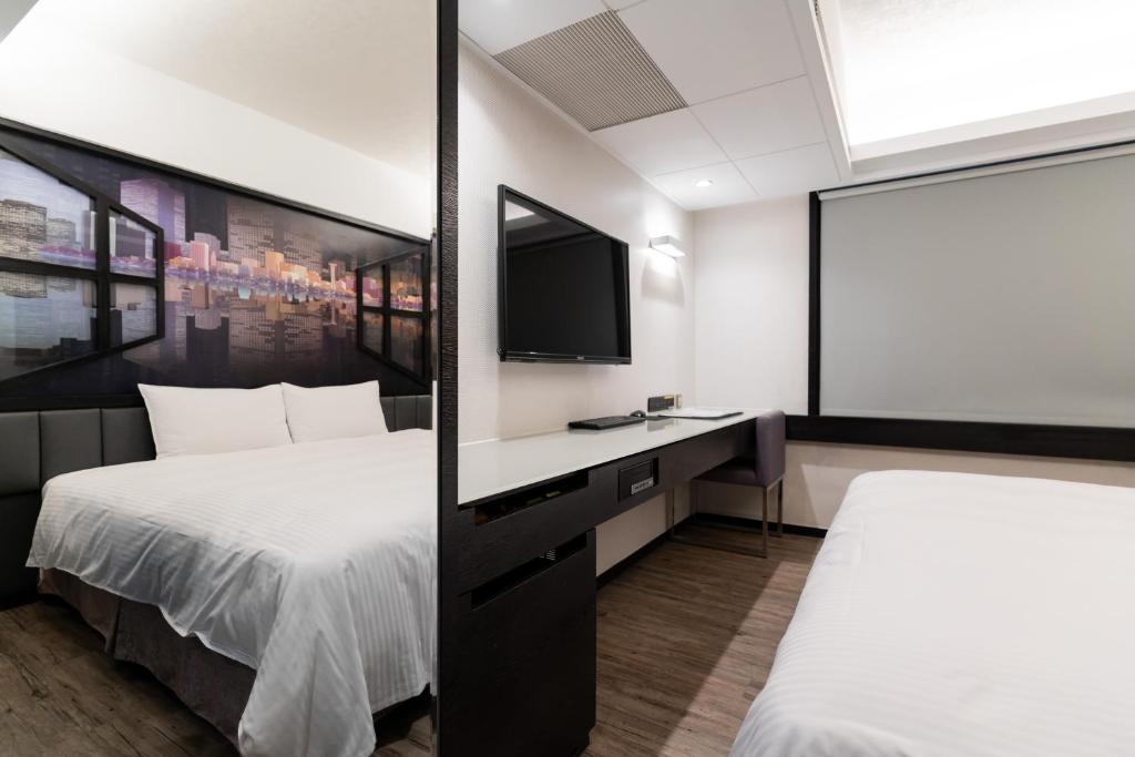 a hotel room with two beds and a flat screen tv at The Cloud Hotel in Kaohsiung