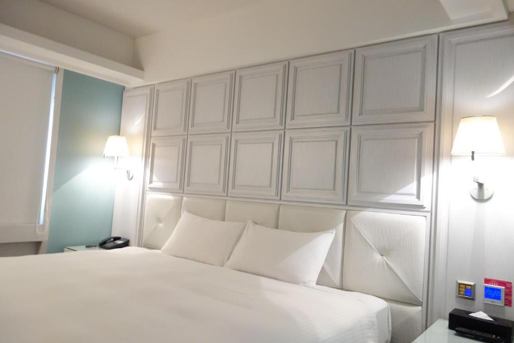 a bedroom with a white bed with two white pillows at The Cloud Hotel in Kaohsiung