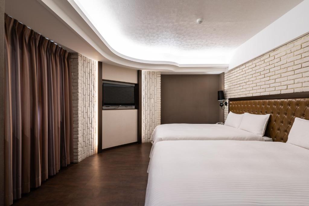a hotel room with two beds and a brick wall at The Cloud Hotel in Kaohsiung