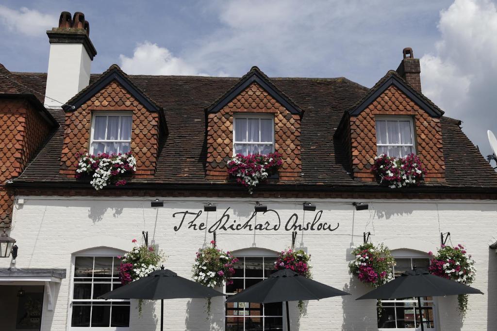 - un bâtiment blanc avec des parasols en face dans l'établissement The Richard Onslow, à Cranleigh