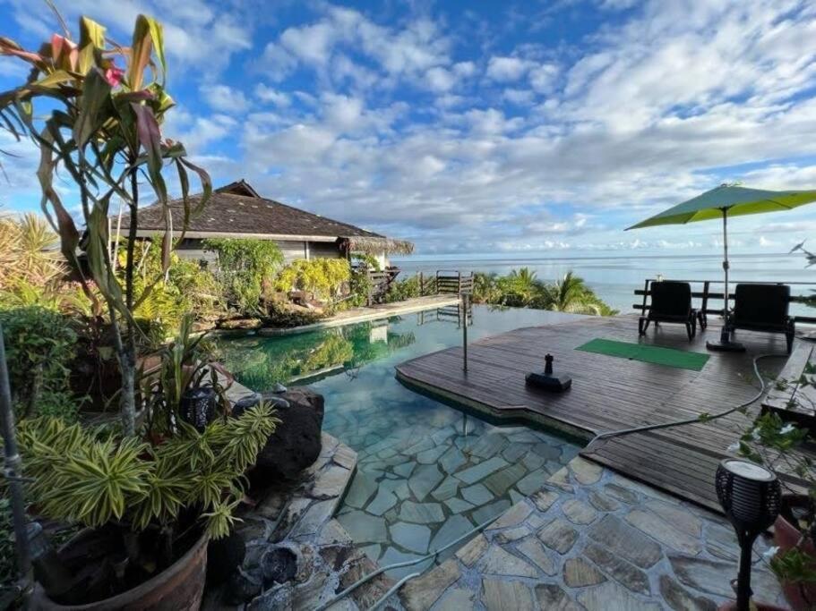 una piscina con terraza y vistas al océano en Tehuarupe Surf Studios en Haapiti
