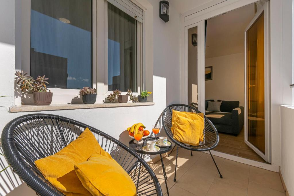 a balcony with two chairs and a table with yellow pillows at Apartment Cute in Omiš