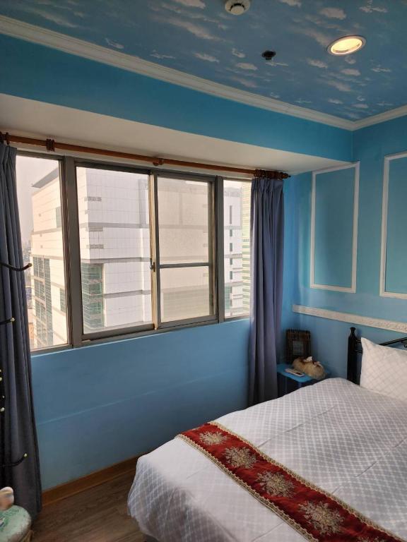a bedroom with blue walls and a bed with a window at MB Hotel in Kaohsiung