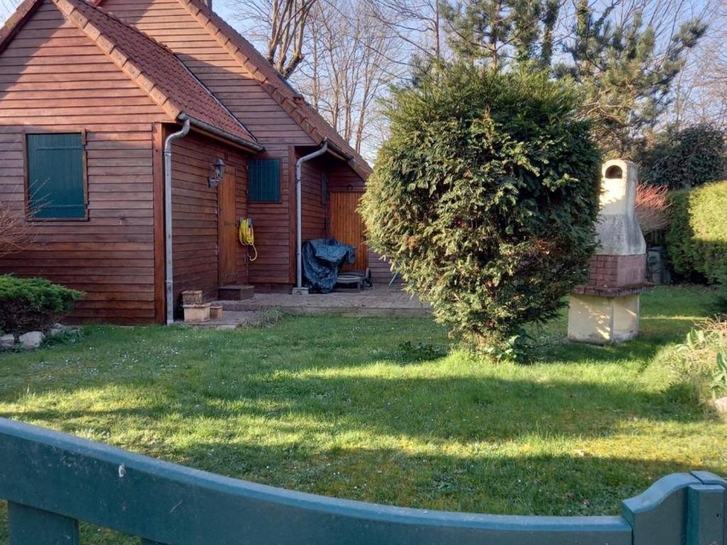 une maison avec une cour avec un bush devant elle dans l'établissement Charmant chalet avec jardin, proche plage et centre-ville de Berck, idéal pour familles avec enfants - FR-1-646-46, à Berck-sur-Mer