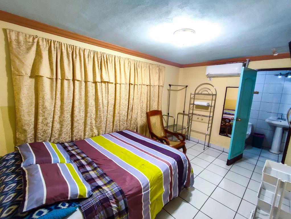 a bedroom with a bed and a chair and a mirror at Hotel Fuente de Paz Managua in Managua