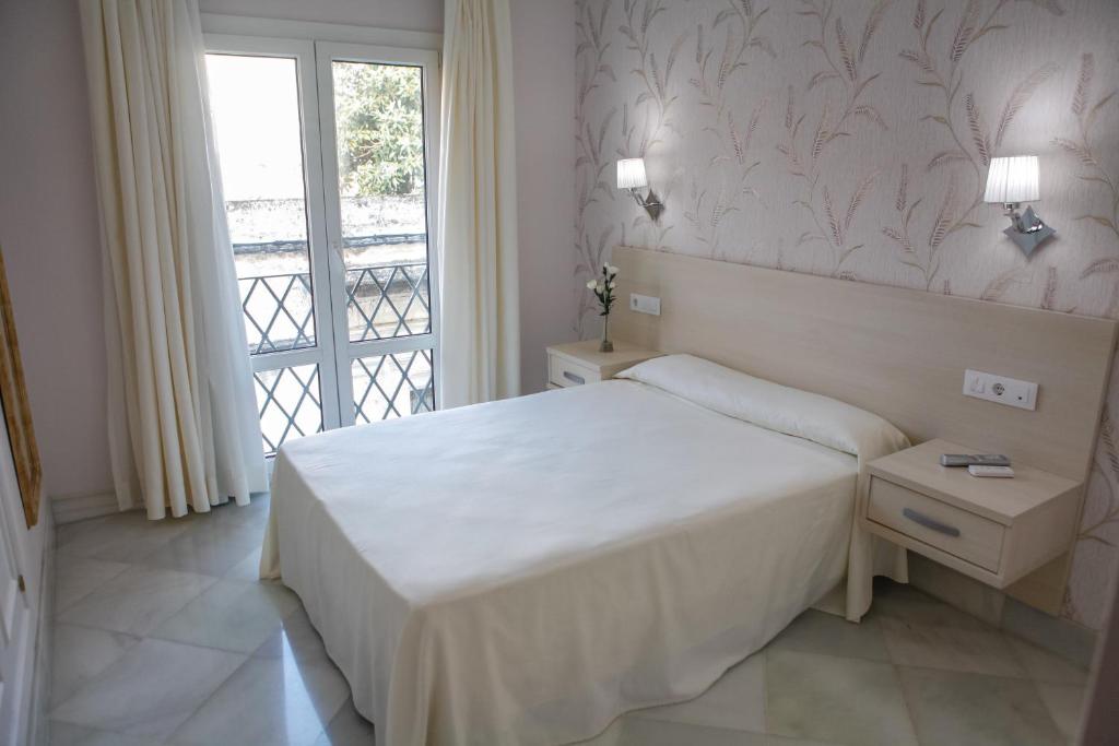 a white bedroom with a bed and a window at Chaikana in El Puerto de Santa María