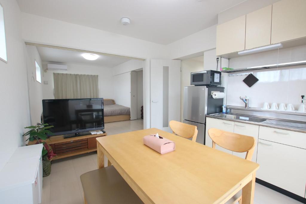 a living room with a table and a kitchen at SAPPHIRE -SEVEN Hotels and Resorts- in Okinawa City