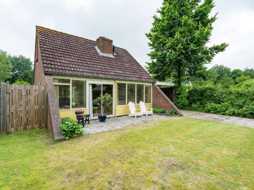 ラウエルウオーフにあるCosy holiday home in Lauwersoogの小さな家で、パティオ(白い椅子2脚付)が備わります。
