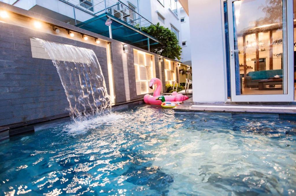 a pool with a water fountain and a pink flamingo toy at Villa Pearl FLCSầm Sơn in Sầm Sơn