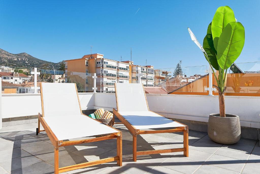 two white chairs on a balcony with a plant at Solaga - Jabega in Málaga