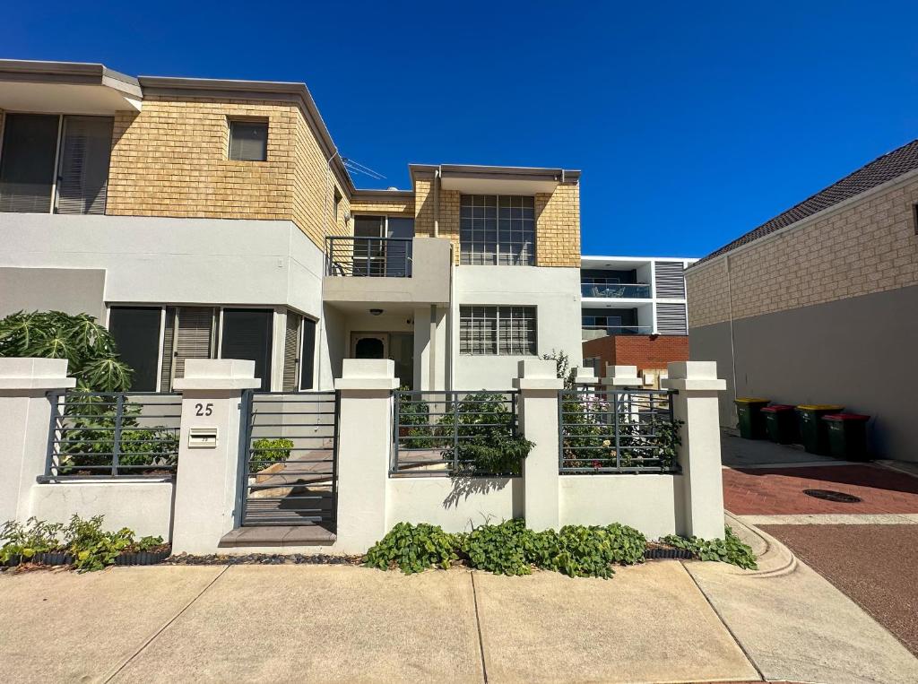 ein weißes Haus mit einem Tor und einem Gebäude in der Unterkunft Joondalup Guest House in Perth