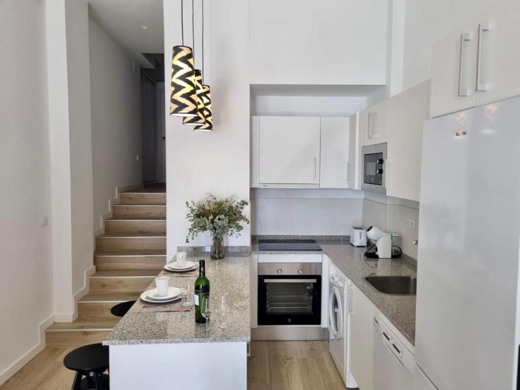 a kitchen with white cabinets and a counter with a bottle of wine at Apartamentos RG Hospital Valme in Seville