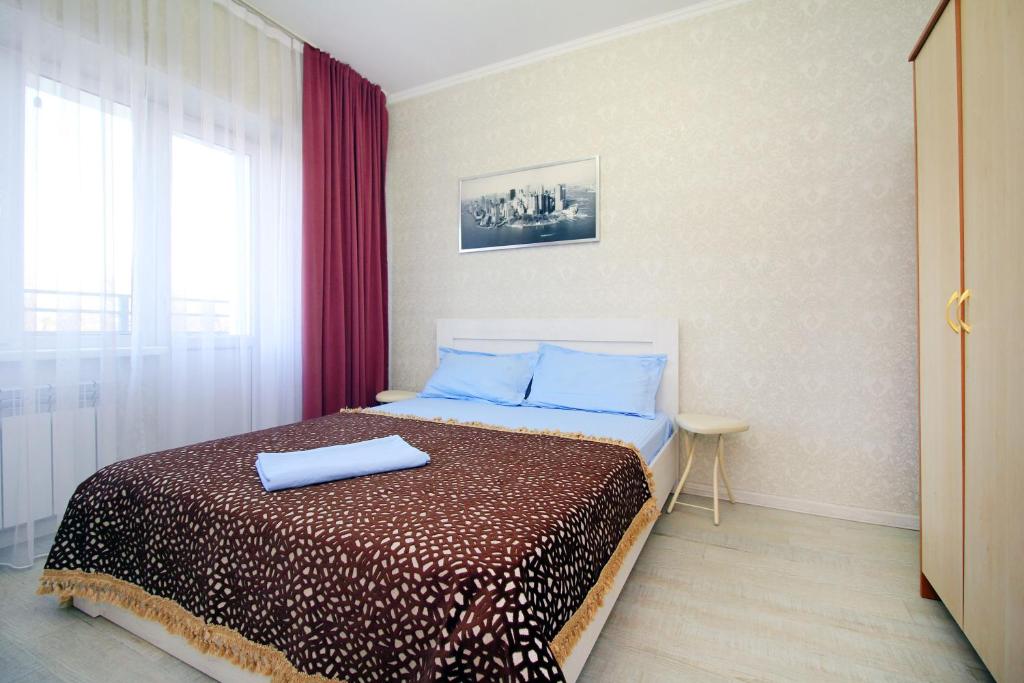 a bedroom with a bed with blue pillows and a window at ЖК Радужный берег РБ 14 in Turksib