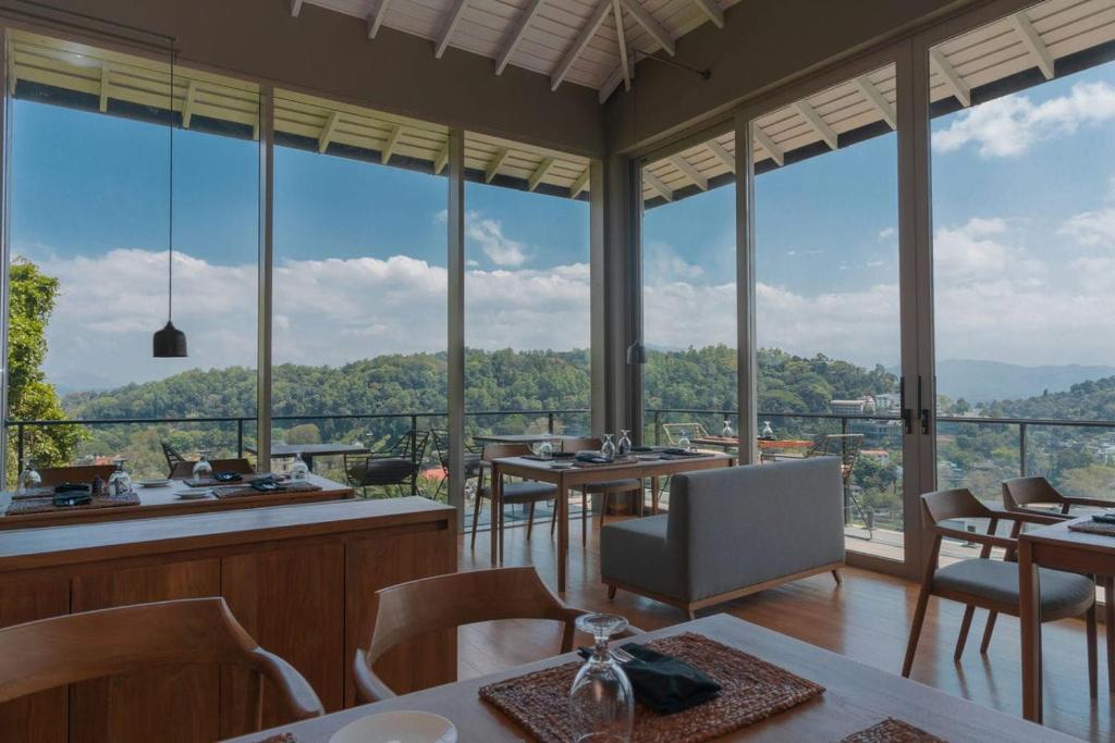 un restaurante con mesas, sillas y ventanas grandes en Rivora Heights en Kandy