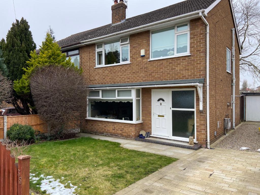 uma casa de tijolos com uma porta branca em Cumberland Avenue prenton Wirral 3bed detached house with a lovely view looking out on to a field from the rear close to all amenities em Birkenhead