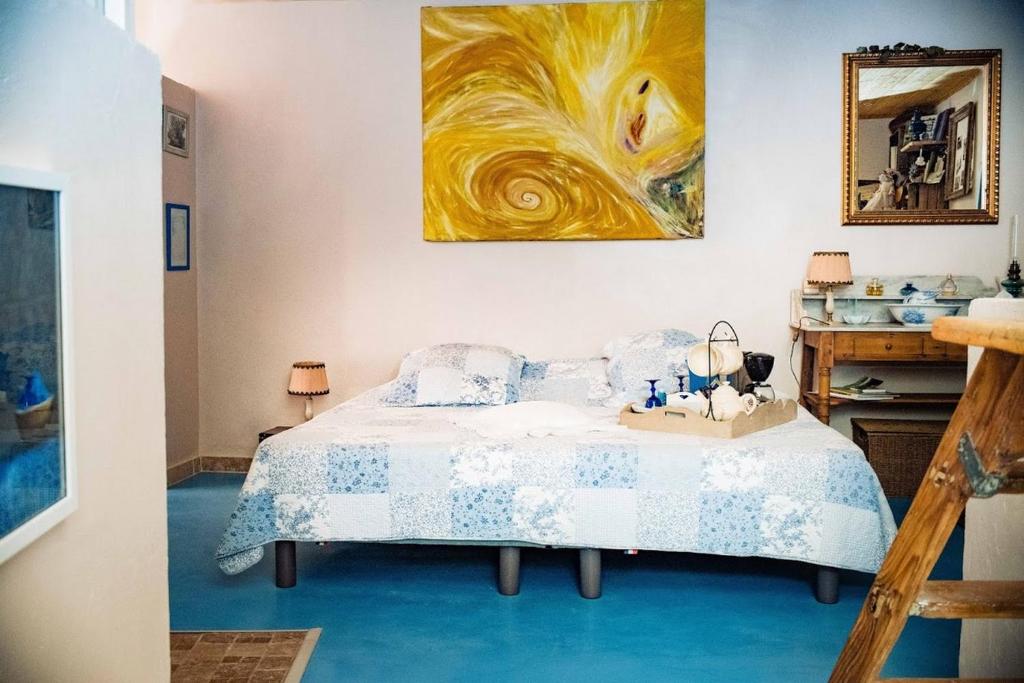 um quarto com uma cama e um quadro na parede em Fa Mille Maison Bleue em Robion en Luberon