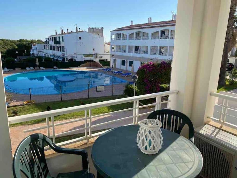 a table on a balcony with a view of a pool at Calan Blanes con piscina in Ciutadella