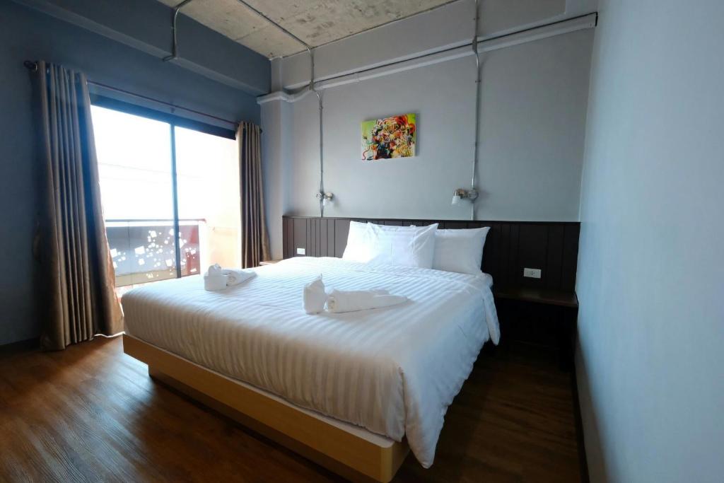 1 dormitorio con 1 cama blanca grande y ventana grande en Room2u, en Hat Yai