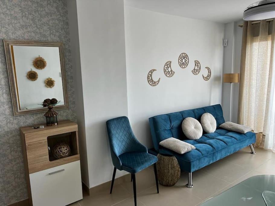 uma sala de estar com um sofá azul e uma cadeira em Atico Duplex en Playa Serena em Roquetas de Mar