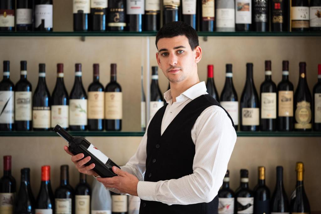 a man holding a bottle of wine in a wine store at Hotel Miranda in Riva di Solto