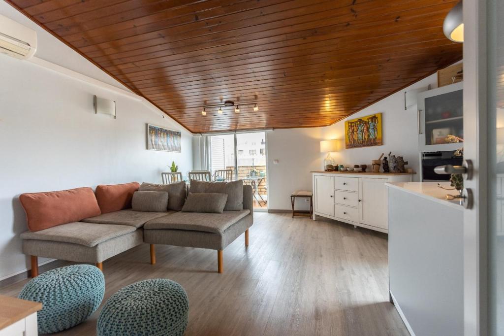 ein Wohnzimmer mit einem Sofa und einer Küche in der Unterkunft THE ATTIC - Caparica Beach and Surf Apartment in Costa da Caparica