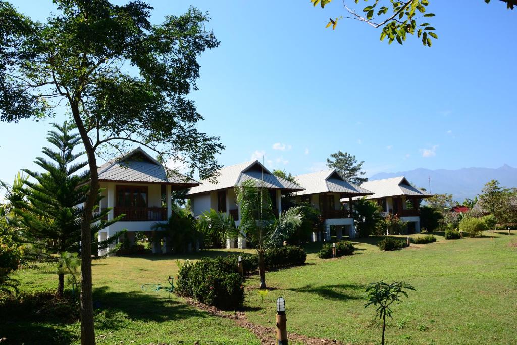 eine Reihe von Häusern mit Bäumen auf einem Feld in der Unterkunft Pai Loess Resort in Pai