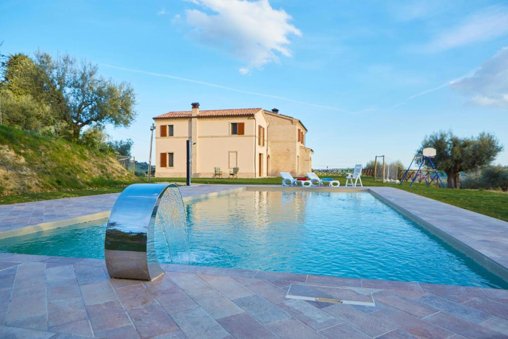 a swimming pool in front of a house with a building at Agriturismo Nido delle Rondini in Macerata