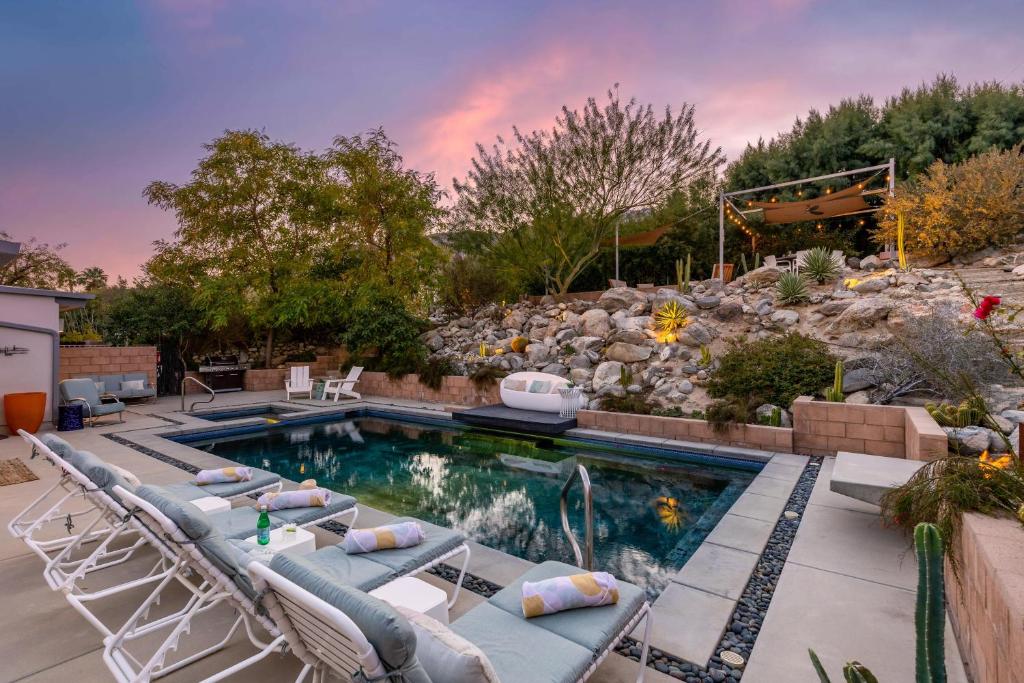 a backyard pool with chairs and a rock wall at On The Rocks in Palm Springs