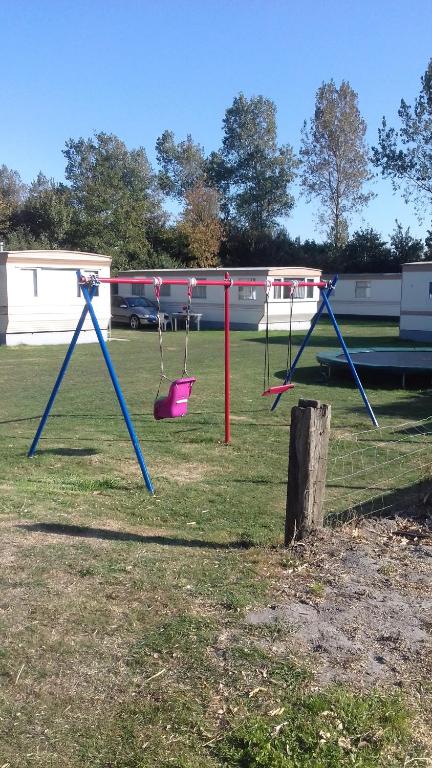 einen Spielplatz mit zwei Schaukeln auf einem Feld in der Unterkunft Middenin in Grijpskerke