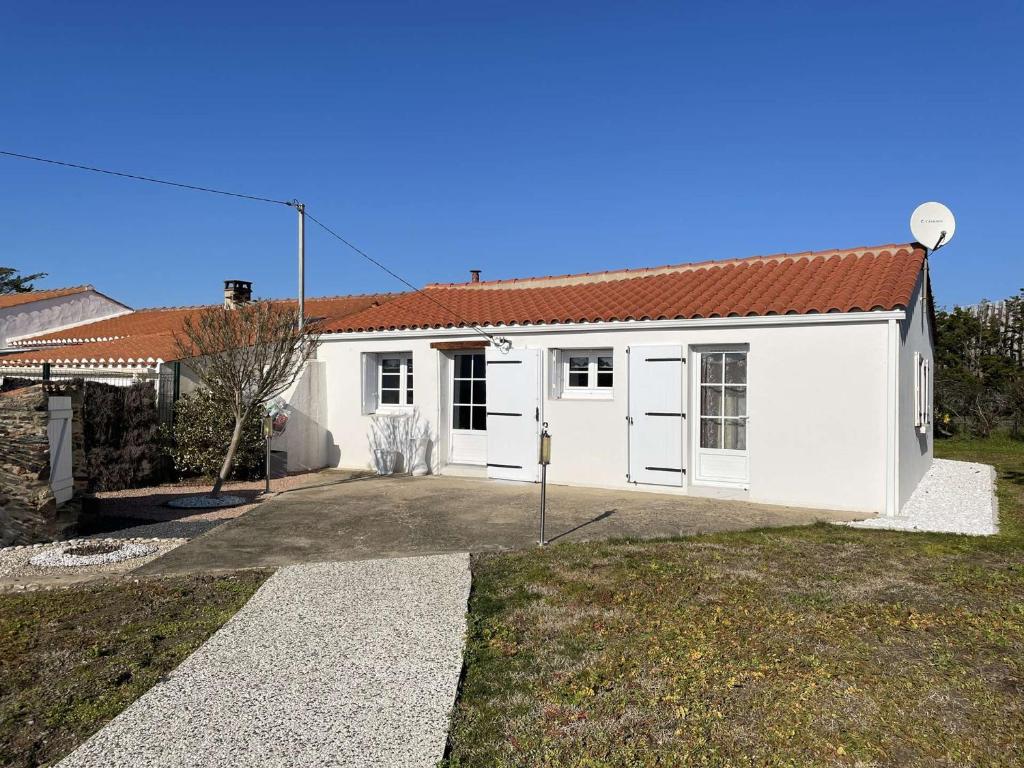 une maison blanche avec un toit rouge dans l'établissement Maison 3 pièces avec jardin clos, terrasse, et équipements à 1,9 km de la plage - 6 couchages - FR-1-224-779, à Saint-Gilles-Croix-de-Vie