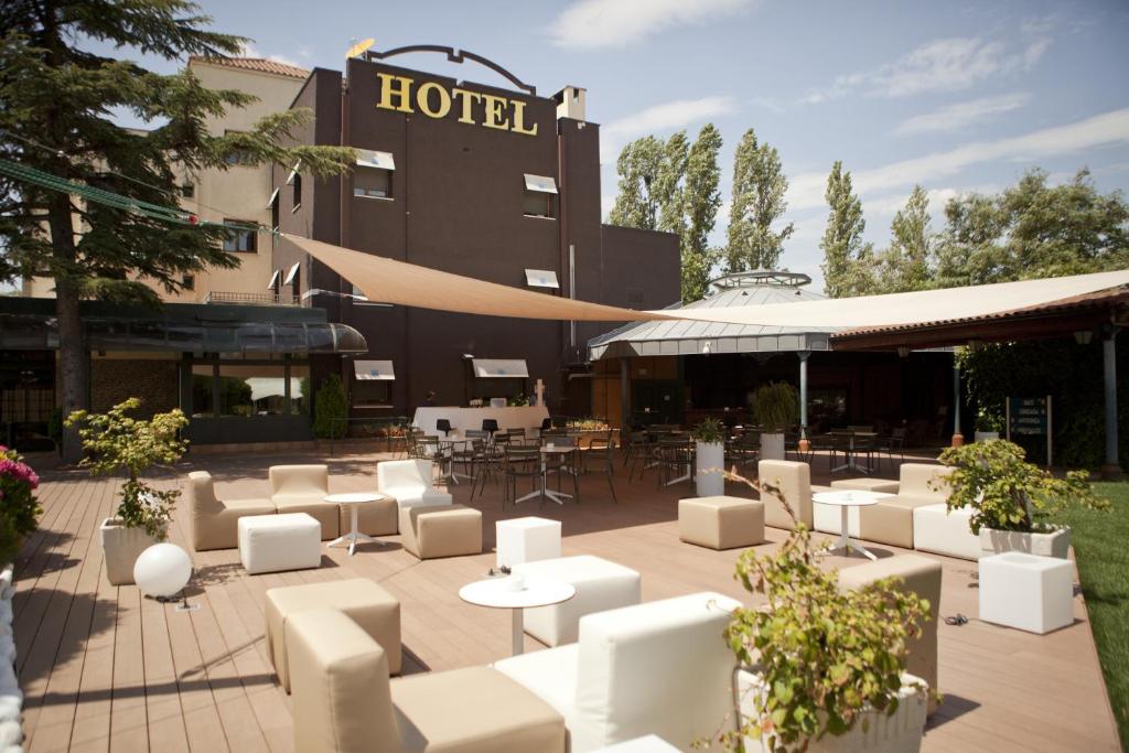 un hôtel avec des chaises et des tables blanches en face d'un bâtiment dans l'établissement Don Carlos, à Huarte