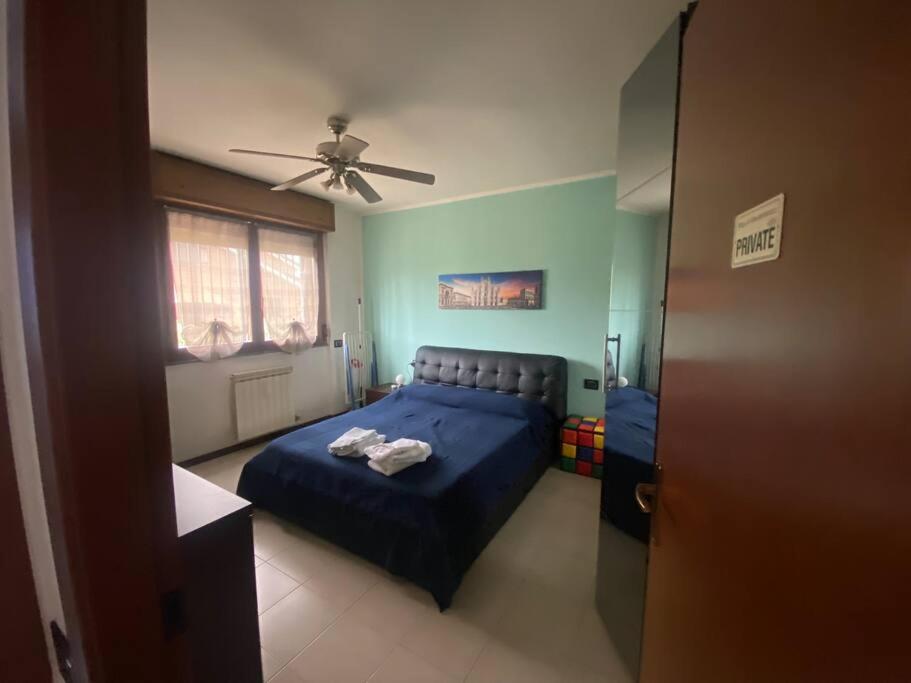 Schlafzimmer mit einem blauen Bett und einem Deckenventilator in der Unterkunft Fuori Milano molto tranquillo (box incluso) 