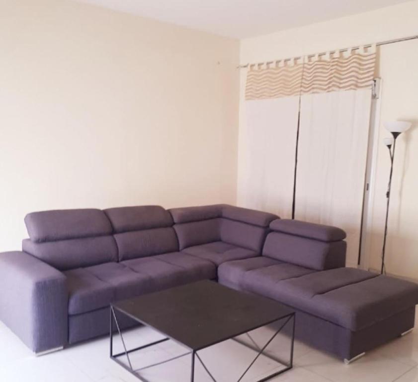 a living room with a purple couch and a table at ZAC MBAO - Cité enseignants in Kammba