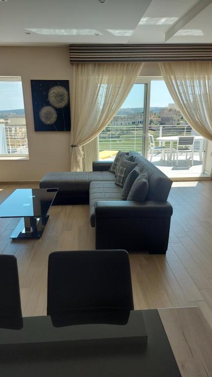 a living room with a couch and a table at Trilogy, Ample Penthouse, Gozo in Kerċem