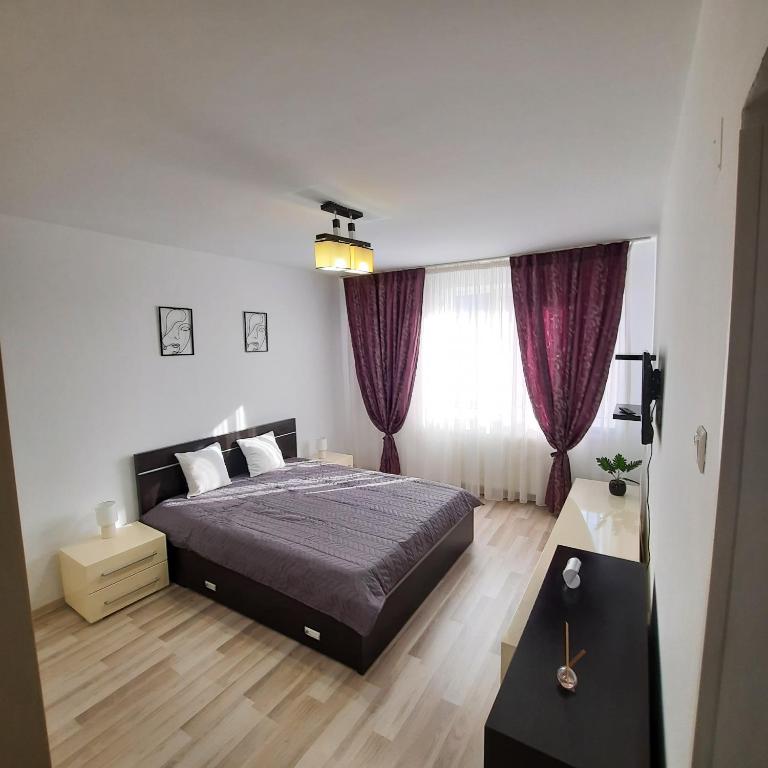a bedroom with a large bed with purple curtains at Apartament KEPA din Piatra Neamt in Piatra Neamţ