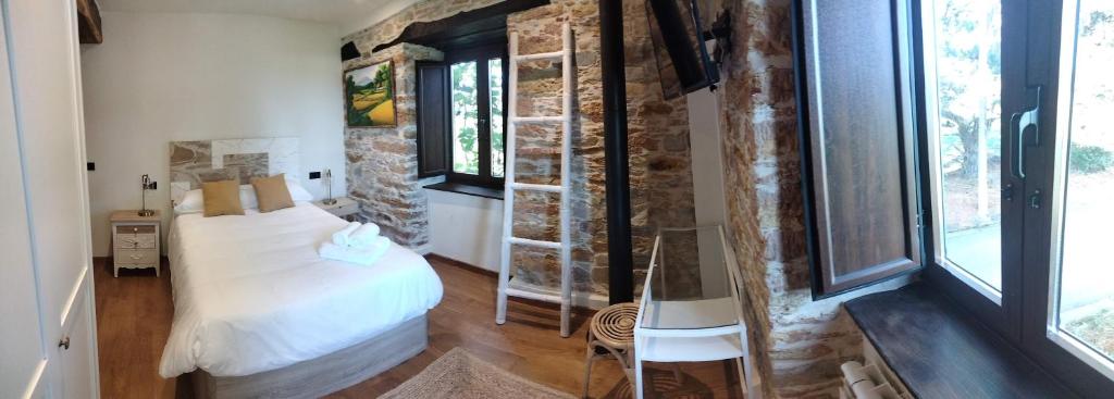 1 dormitorio con cama y pared de piedra en Casa Bagaro, en Serantes