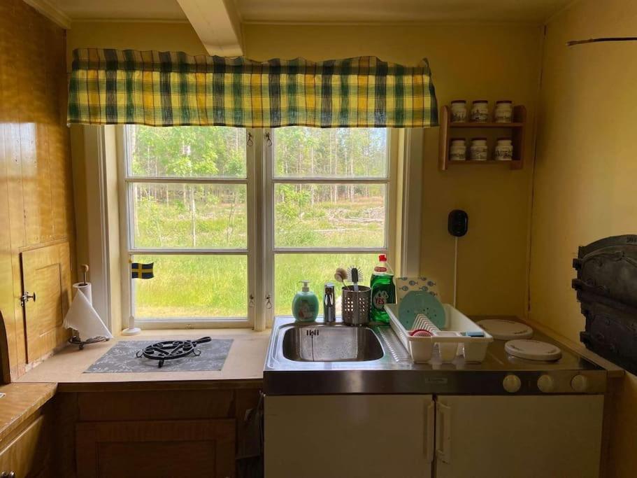 cocina con fregadero y ventana en Fint torp nära vattnet med tillgång till båt., en Mellerud