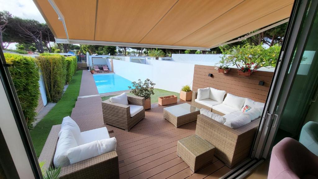 un patio al aire libre con sofás y sillas y una piscina en Casa do Pai Beach House, en Aldeia do Meco