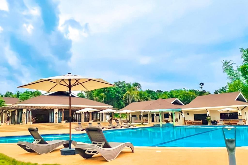 a swimming pool with chairs and an umbrella at FIG Sunset View Resort in Siquijor