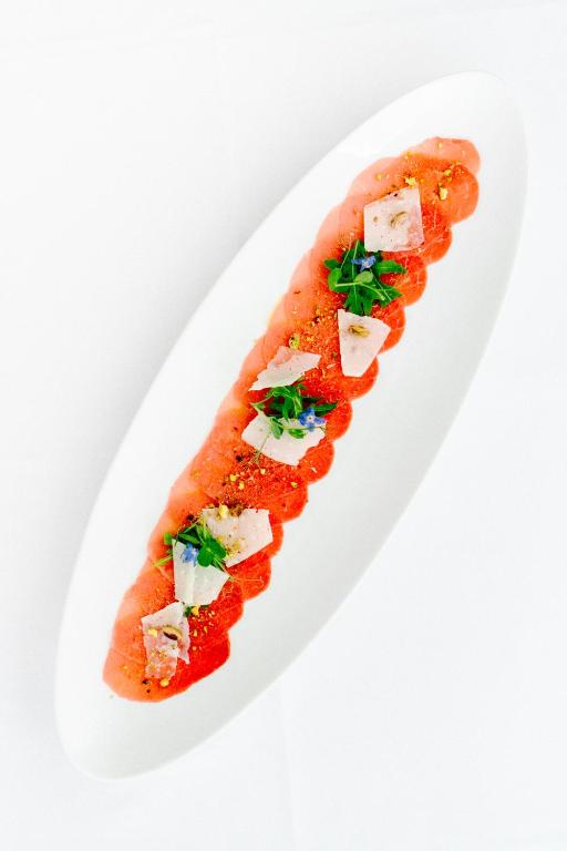 a white plate with a fish dish on it at Hotel Grahor Depandance in Sežana