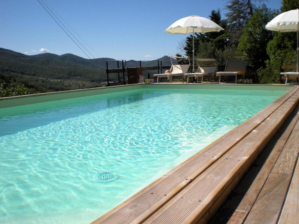 una piscina con banco y sombrilla en Farmhouse in Cortona wit garden and pool, en Cortona