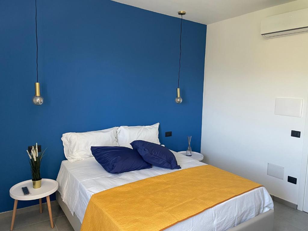 een blauwe slaapkamer met een bed met een gele deken bij Tresino Rooms in Agropoli